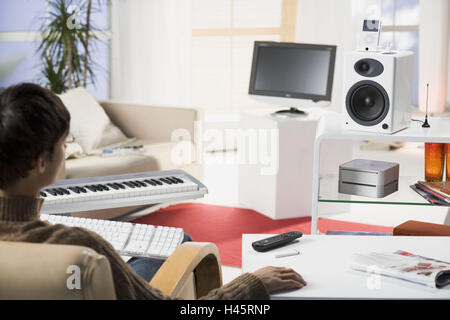 Living room, man, young, sitting, back view, detail, no property release, series, people, screen, TVs, lcd-TV-set, loudspeakers, Mac mini, iPod video, Apple Remote, electronics, electro-appliances, technology, conversation, conversation-electronics, servi Stock Photo