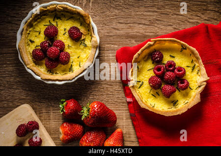 Lemon tart with rosemary and berries, filled with cream topped berries Stock Photo