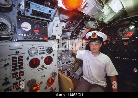 Young boy wearing a Navy officer peak cap saluting from the Helm of the Pilot's station onboard Oberon class submarine HMS Ocelot. HM Submarine Ocelot Stock Photo