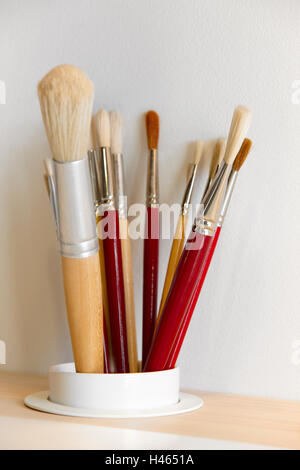 Different kinds of paintbrushes over a wooden table. Vertical