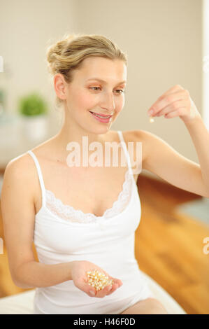 Young woman is holding capsules in the hand, Stock Photo