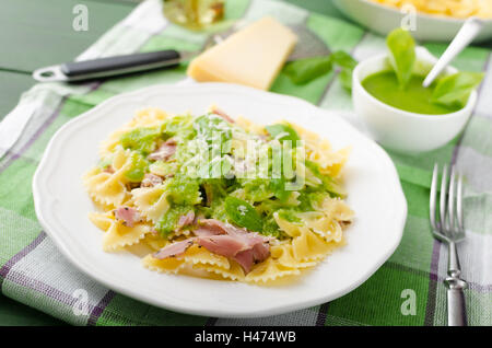Pasta with pesto, smoked bacon and basil. Domestic pesto with oil, basil, nuts, garlic and parmesan cheese. Stock Photo