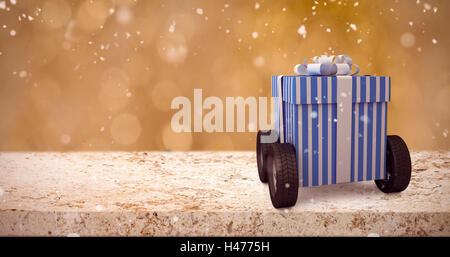 Composite image of blue and white striped gift box on wheels Stock Photo
