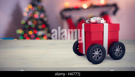 Composite image of gift box wrapped in red paper with ribbon on wheels Stock Photo