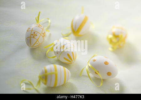 White Easter eggs yellow paints on pale green table caps, Stock Photo