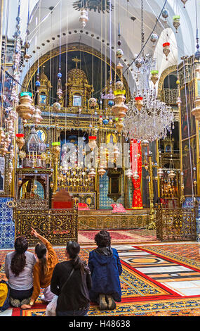 The interior of St James Cathedral with hundreds of oil lamps, wooden carved altar, covered with gold, Jerusalem, Israel Stock Photo