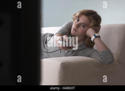 Girl lies on the sofa and watches TV, Stock Photo