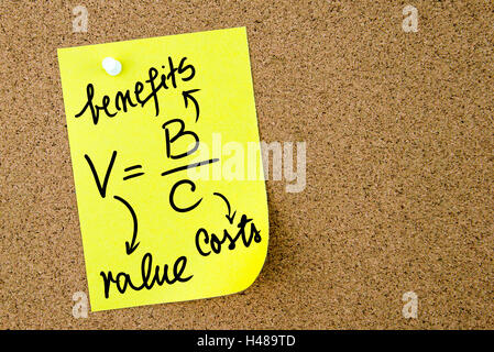 Value is Benefits per Costs text written on yellow paper note pinned on cork board with white thumbtack. Business concept image Stock Photo