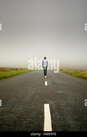 Man stands in the middle of an empty road in Dartmoor, England Stock Photo