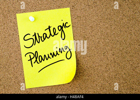 Strategic Planning text written on yellow paper note pinned on cork board with white thumbtack. Business concept image Stock Photo