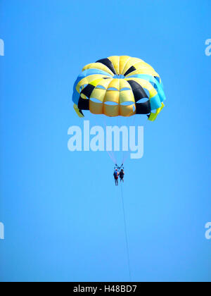 Parasailing in the blue sky, coloured parachute, two people,