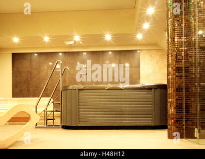 Indoor jacuzzi with metal stairs in a mosaic walled bathroom, in relaxing ambient light Stock Photo