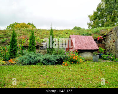 traditional old water well with wooden roof in an autumn country garden Stock Photo