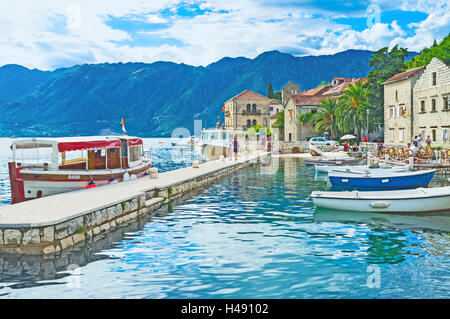 The small fishing port in the city centre with the moored boats and tourist ships, Perast, Montenegro. Stock Photo