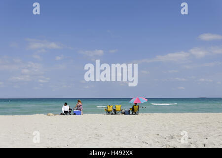 Woman sits on cool box, beach life, beach paragraph, suture 77 Street, Miami South Beach, Atlantic, Florida, USA, Stock Photo