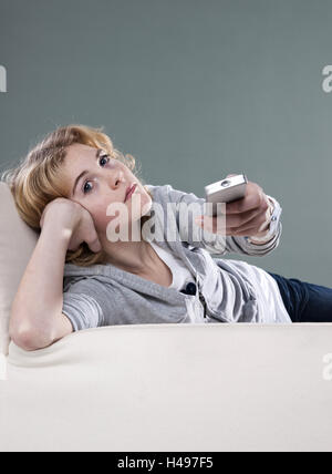 Girl lies on the sofa and watches TV, Stock Photo