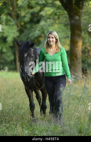Teenage girl, horse, Arabian Haflinger, meadow, frontal, leading, looking at camera, Stock Photo