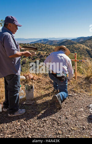 Bisbee, Arizona - Members of the School Sisters of Notre Dame and their supporters plant a cross in Mule Mountains near the spot where the remains of an unidentified migrant were found. Hundreds of migrants from Mexico and Central America have perished in recent years as they tried to evade U.S. Border Patrol checkpoints. More than 400 crosses in the Arizona desert, planted by SSND and other groups, now mark the spots where they died. The cross is decorated with bottle caps found in the desert from water bottles carried by migrants. Credit:  Jim West/Alamy Live News Stock Photo