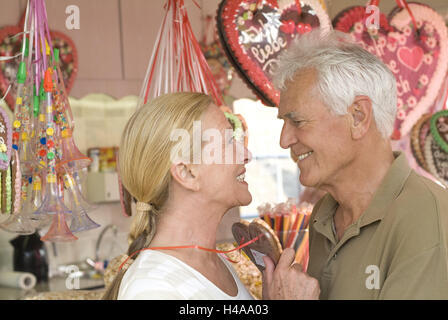 Funfair, senior couple, happy, eye contact, gingerbread heart, portrait, side view, Stock Photo
