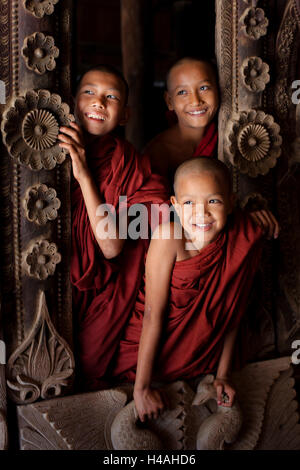 Three young novice monks in Shwenandaw monastery near Mandalay, Myanmar Stock Photo