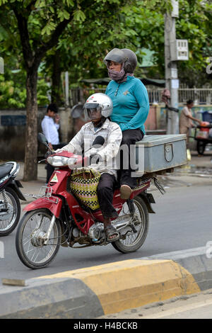 Man on moped and woman sitting on a box, Phnom Penh, Cambodia Stock Photo