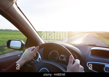 Hands of young driver on steering wheel during road trip with rental car Stock Photo