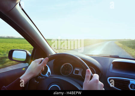 Person driving car with blue sky and green grass Stock Photo