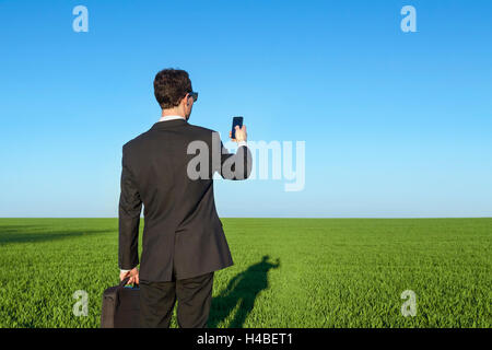 Businessman with smartphone in the field Stock Photo