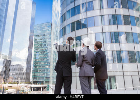 Businessmen and architect team outdoors planning construction project with office buildings Stock Photo