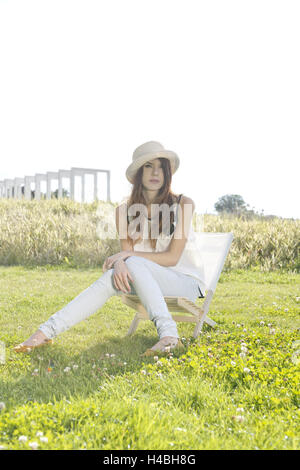 young woman sitting thoughtfully on a meadow, Stock Photo