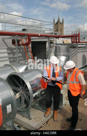 Building Services Engineers inspect new air-conditioning plant on the roof of a central London office building Stock Photo