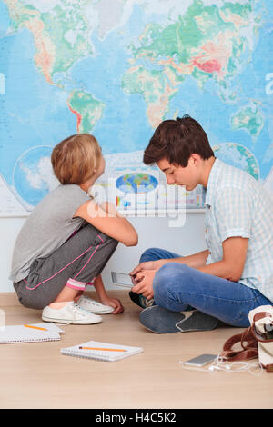 Teenagers sitting by the map in classroom Stock Photo