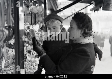 Eine Mutter mit ihrem kleinen Sohn auf dem Weihnachtsmarkt, Deutsches Reich 1930er Jahre. A woman with her little son on the Christmas market, Germany 1930s Stock Photo