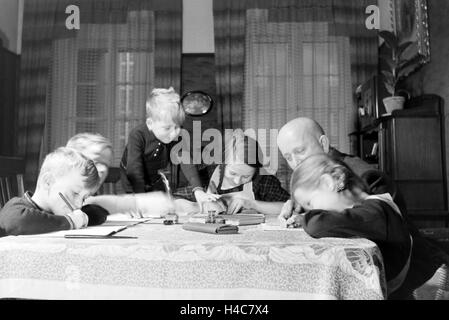 Mitglieder einer kinderreichen Familie bei den Hausaufgaben, Deutsches Reich 1930er Jahre. Members of a extended family doing the homework, Germany 1930s Stock Photo