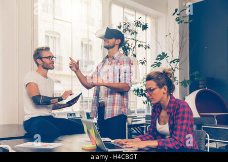 Entrepreneurs testing virtual reality technology with colleague in office. Stock Photo