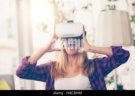 Amazed woman looking in a VR goggles and gesturing Stock Photo