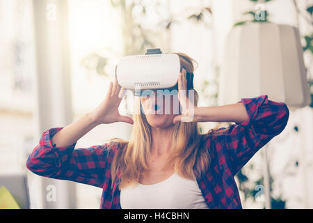 Amazed woman looking in a VR goggles and gesturing Stock Photo