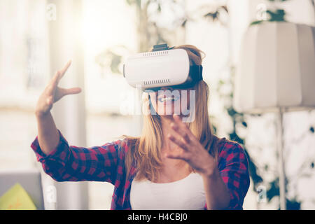 Amazed woman looking in a VR goggles and gesturing Stock Photo