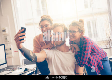 Friends at work taking self portrait with camera phone Stock Photo