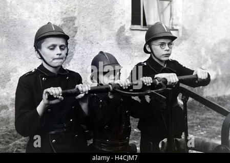Jungen von der Kinderfeuerwehr betätigen bei einem Übungseinsatz die Wasserpumpe, Deutschland 1930er Jahre. Boys of the junior firefighters using the hand pump during a training, Germany 1930s Stock Photo