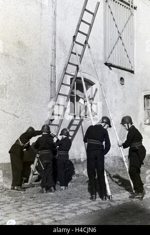 Eine Gruppe von der Kinderfeuerwehr stellt während einer Feuerwehrübung eine Leiter auf, Deutschland 1930er Jahre. A group of junior firefighters is preparing a ladder during a firefighter training, Germany 1930s Stock Photo