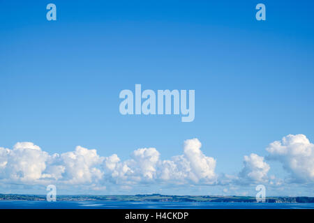 Weather - Cumulus clouds forming in a clear blue sky over a coastline - England, UK Stock Photo