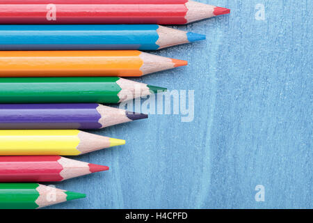 some crayons aligned on a horizontal composition on blue background Stock Photo