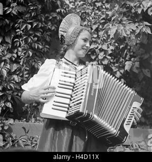 Eine junge Frau in der Tracht der Wachau in Österreich mit einem Akkordeon, Deutschland 1930er Jahre. A young woman wearing the array of the Wachau area in Austria with an accordion, Germany 1930s. Stock Photo