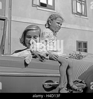 Ein Mädchen, ein Hund und eine junge Frau in einem Cabrio, Österreich 1930er Jahre. A little girl, a puppy and a young woman in a convertible, Austria 1930s. Stock Photo