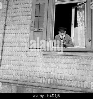 Ein Mann raucht seine Pfeife und schaut dabei aus dem Fenster, Deutschland 1930er Jahre. A man smoking his pipe while watching out of the window, Germany 1930s. Stock Photo