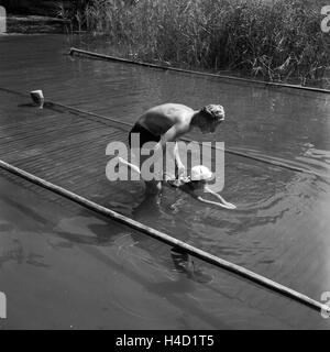 Ein Vater bringt seinem Sohn das Schwimmen bei, Deutschland 1930er Jahre. A father teaches his son how to swim, Germany 1930s. Stock Photo