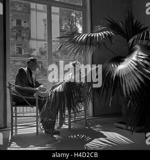 Ein Mann und eine Frau sitzen an einem Fenster einer Hotellobby in Wildbad im Schwarzwald, Deutschland 1930er Jahre. A man and a woman sitting by a window of a hotel lobby at Wildbad in Black Forest, Germany 1930s. Stock Photo