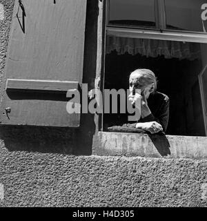 Eine alte Frau schaut aus ihrem Fenster heraus in Regensburg, Deutschland 1930er Jahre. An old woman watching out of her window at Regensburg, Germany 1930s. Stock Photo