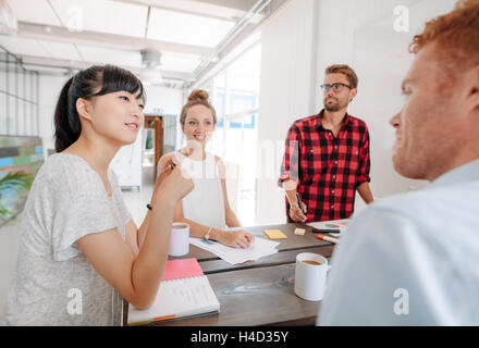 Diverse group of young business people at presentation in the office. Coworkers sitting around a table in modern office. Stock Photo